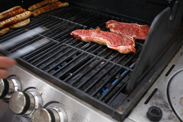 Steaks auf Gasgrill und Zange