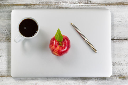 Laptop With Fresh Red Apple And Coffee On Top Of Old Desktop