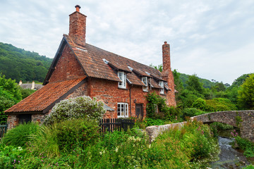 malerisches Cottage mit historischer Packpferdbrücke in Allerford, Somerset, England
