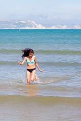 hübsches junges Mädchen läuft am Meer durchs Wasser
