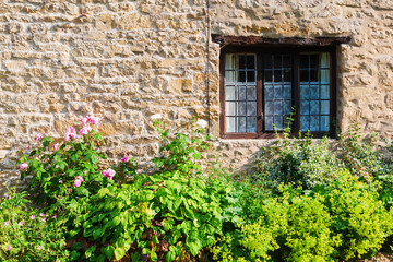 Fototapeta na wymiar pflanzenumranktes Fenster eines alten Cottages in Bibury, England