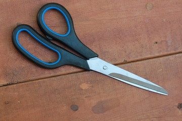 Black and blue handled scissors on wood background