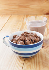 Chocolate cornflakes on wooden background with chocolate milk in