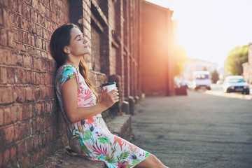 pretty girl sitting in street with morning coffee and relaxing