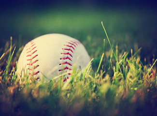 a baseball in a grass background toned with a vintage retro instagram