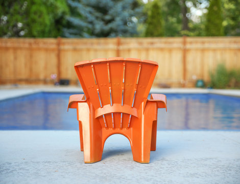 Blue Swimming Pool And Empty Orange Chair During Summer