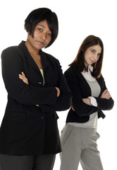 Two businesswomen standing with arms crossed. Focus is on woman in front.