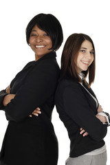 Two women stand back to back smiling at viewer.