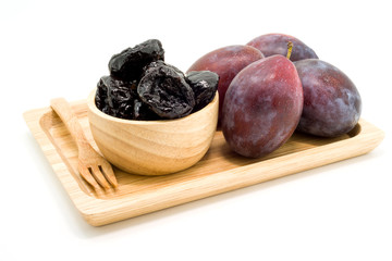Delicious prunes in wooden bowl and fresh plums