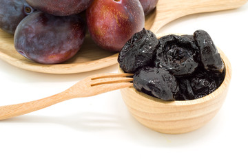 Delicious prunes in wooden bowl and fresh plums