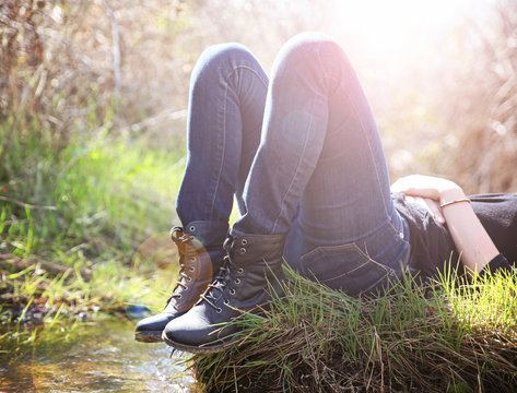 a girl lying on a small island in a stream with jeans and black
