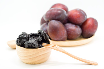 Delicious prunes in wooden bowl and fresh plums