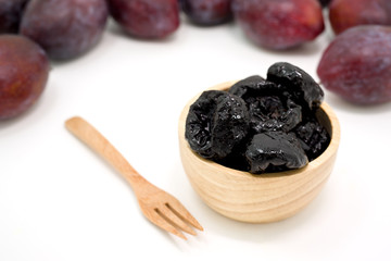 Delicious prunes in wooden bowl and fresh plums