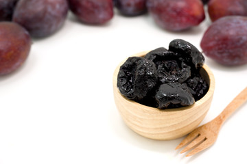 Delicious prunes in wooden bowl and fresh plums