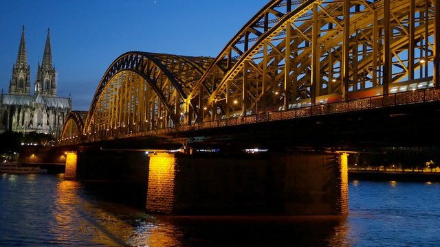 Gothic Cathedral and iron bridge across Rhine river after sunset. Cologne, Germany