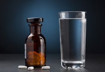 Medicine pills bottle and glass of water