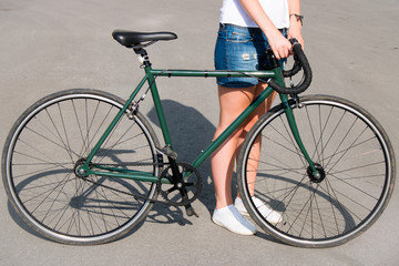 Naklejka premium young woman standing on the road next to a green bike