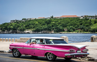HDR - Kuba pinker amerikanischer Oldtimer parkt auf der Malecun Promenade in Havanna mit Blick auf...