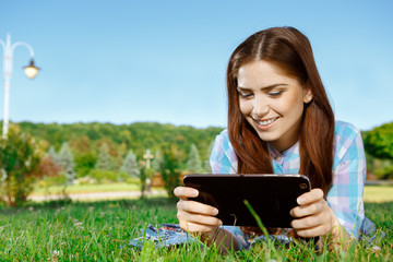 Fototapeta premium Beautiful girl in park with touchpad