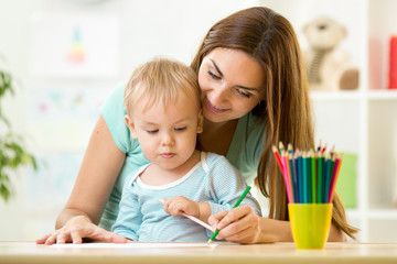 Obraz na płótnie Canvas Mother helping her kid to make drawings