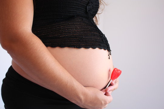 Embarazada esperando a su bebe con piruleta en la mano