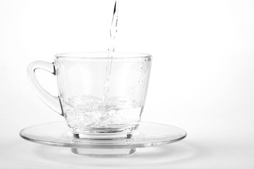 Pouring water into glass from a bottle, on white background