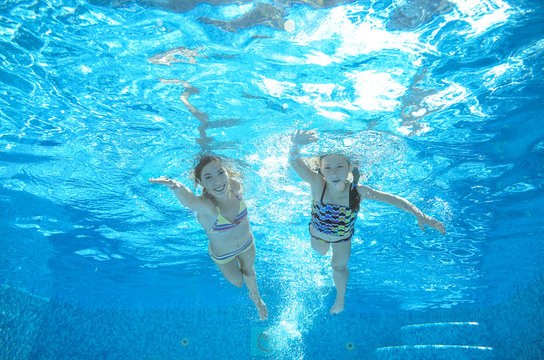 Children swim in pool underwater, happy active girls have fun in water
