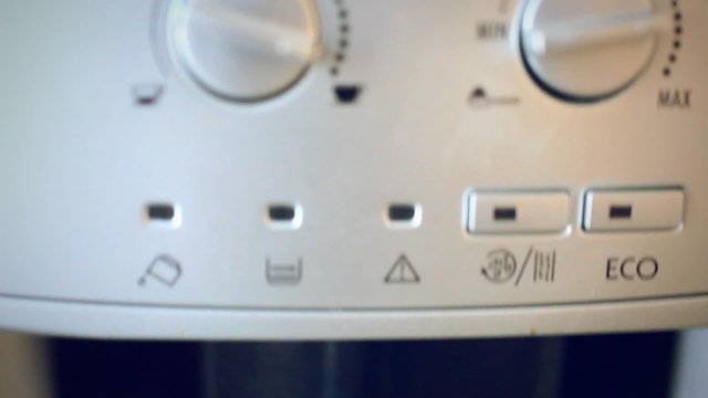 Finger presses the button on the automatic coffee espresso