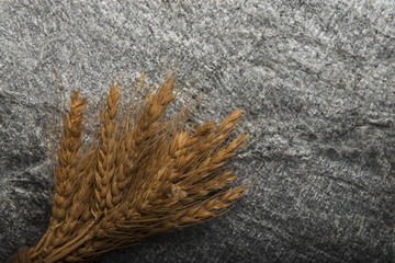 Dried wheat and straw on stone background