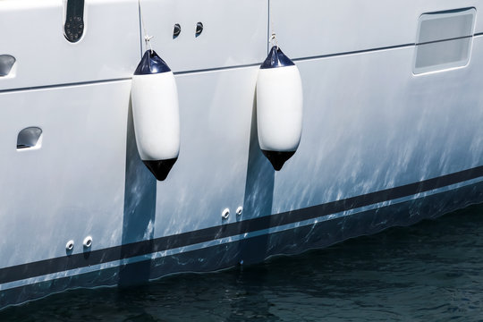 Fototapeta Small ship fenders hanging above white yacht hull