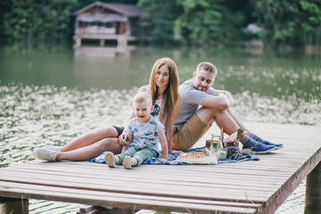 Fototapeta na wymiar Beautiful happy family having picnic near lake
