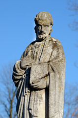 Old stone statue at the tomb of the evangelist in the old cemete