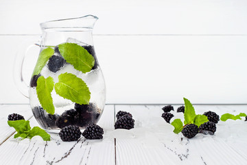 Healthy detox water with blackberry and mint. Cold refreshing berry drink with ice on white wooden...