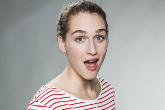 surprise and success concept - beautiful 20s woman wearing a striped sweater expressing surprise and happiness on her face