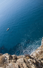 Top view of a deep blue sea and rocks of the coast. little boat