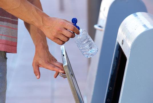 Male hand putting plastic bottle in recycling bin
