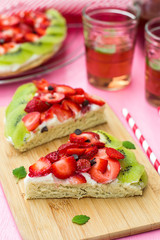 Fototapeta na wymiar Sponge cake with strawberries and kiwi in shape of watermelon