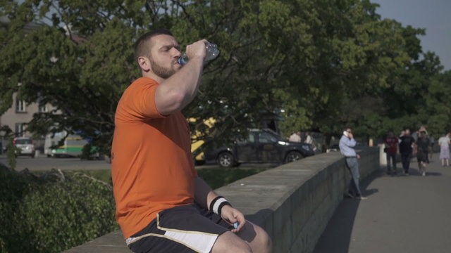 Man is drinking water on wall and starts jogging.
