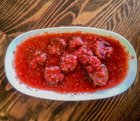 Sliced pickles with chili sauce in a white serving platter