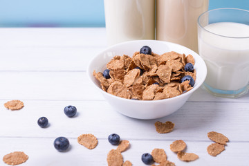 Close view of fresh dairy products with blueberry on wooden table on white wooden background and glass and milk bottles on a back. Shallow depth of field.