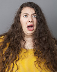 fear concept - young fat woman with long brown hair looking frightened and stressed out with eyes wide opened,closeup in studio shot