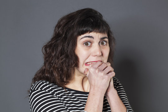 fear concept - frightened 20s woman with brown hair looking stressed out,praying with both hands,studio shot