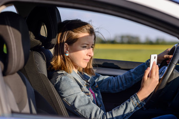 Young female driver reading a text message