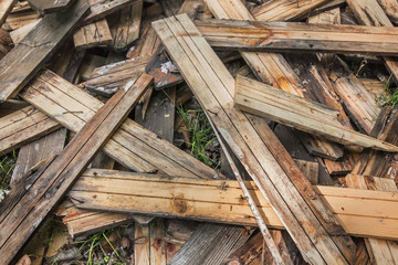 Photograph of old, rotten, scrapped floorboards and decking planks amassed and scattered in a untidy heap.