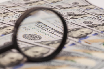 Hundred dollar banknote under magnifying glass