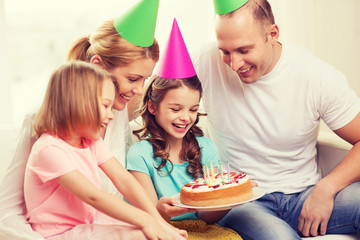 smiling family with two kids in hats with cake