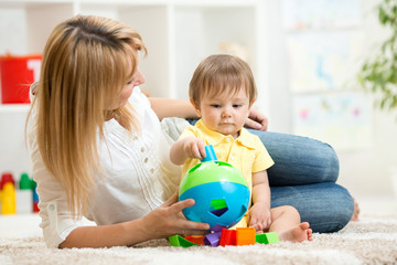 Baby and Mother. Kid boy playing with educational toy.