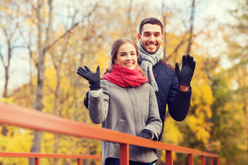 Obraz premium smiling couple hugging on bridge in autumn park