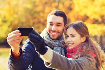 smiling couple with smartphone in autumn park