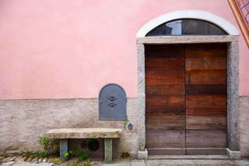 wooden door, pink wall and stone bench